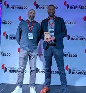 Ali and Iain on stage at the Strathclyde Inspire 100 event, holding the winners' award